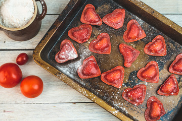 red heart-shaped tomato ravioli on an old baking sheet