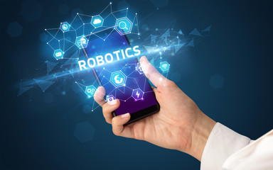 Female hand holding smartphone with ROBOTICS inscription, modern technology concept