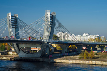 Obraz premium New cable-stayed automobile city bridge with blue expanse of water, blue sky. Betancourt Bridge. Panorama of a modern city. View of the Petrovsky island of St. Petersburg, Russia, May 1, 2019