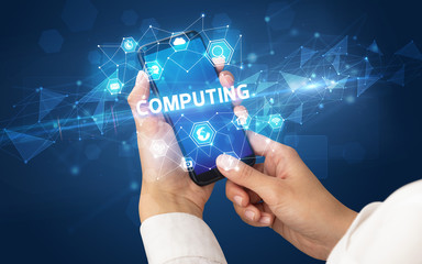 Female hand holding smartphone with COMPUTING inscription, modern technology concept