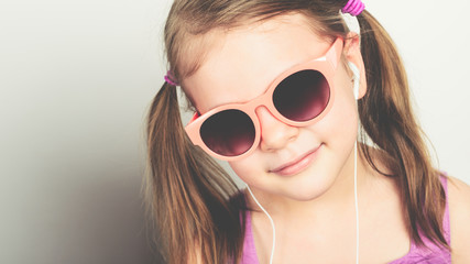 little happy girl in sunglasses and with headphones laughing - studio shot - copy space