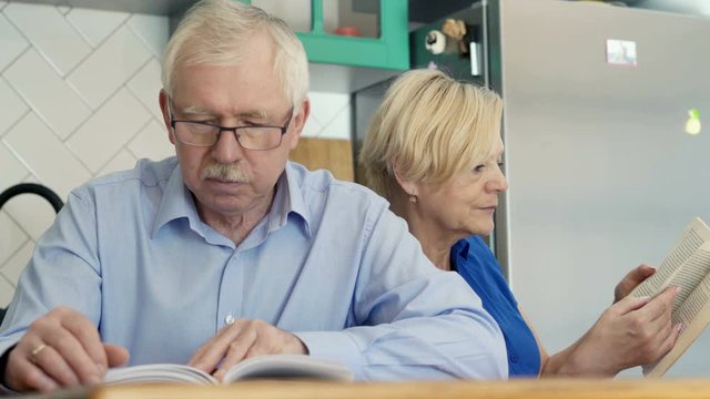 Middle aged couple reading books at home.