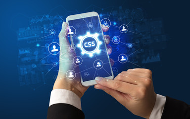 Female hand holding smartphone with CSS abbreviation, modern technology concept