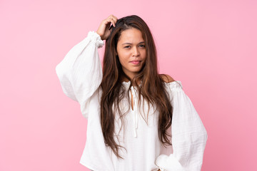 Fototapeta premium Young Brazilian girl over isolated pink background having doubts while scratching head