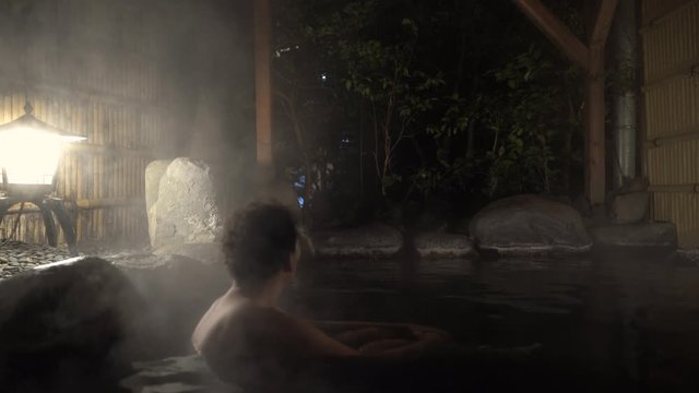 Male sitting inside steamy outdoor Onsen Hot Spring Bath