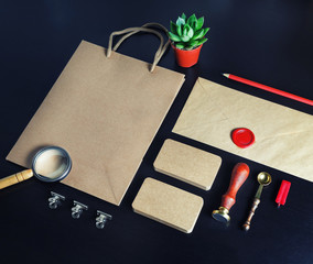 Photo of blank kraft stationery set on black wood table background. Corporate identity mockup....