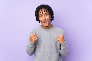 Young african american man isolated on purple background celebrating a victory in winner position