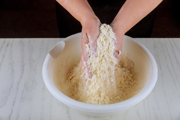 Chef kneading flour, sugar and butter with hands.