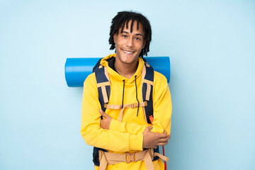 Young mountaineer african american man with a big backpack isolated on a blue background laughing