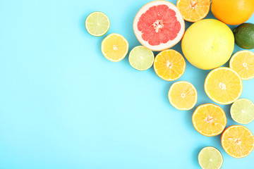 Different citrus and juicy slices on a colored background top view. Place to insert text.