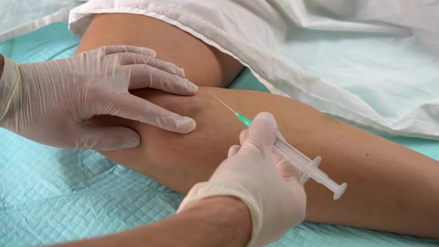 doctor's hands in gloves with a syringe. sclerotherapy.