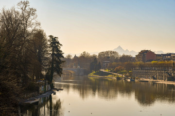 Fototapeta na wymiar Elevated view of Po river with the peak of Monviso Alpine mountain in the background and the Murazzi riverside in winter, Turin, Piedmont, Italy