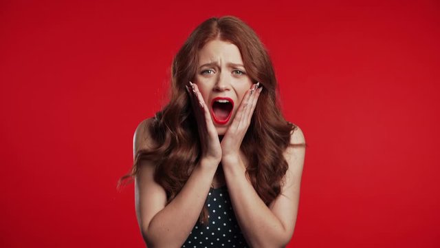 Close up of young frightened screaming girl shocked isolated over red background. Stressed and depressed woman because of bad news