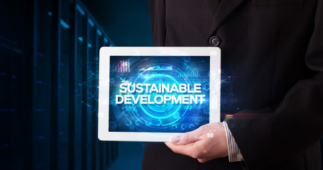 Young business person working on tablet and shows the inscription: SUSTAINABLE DEVELOPMENT, business concept