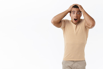 Anxious, concerned young man gambler looking troubled and upset, gasping startled looking camera, dont know what do, facing huge proble, having big debt, grab head shocked, white background