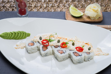 Traditional rolls with fish and rice on a white plate with sauce and wasabi. Japanese food.