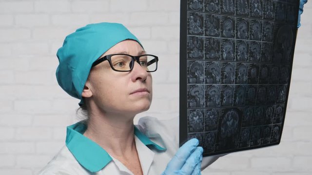 Portrait of female doctor examining MRI images of human brain.