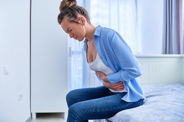 Woman suffering from strong spasm stomach ache during gastric ulcer, appendicitis or...