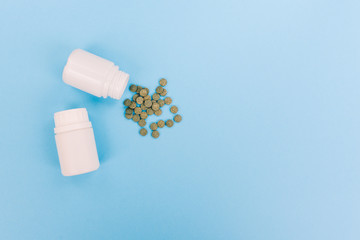 Green scattered tablets. White plastic jars with drugs, vitamins and antibiotics. Treatment of diseases with medicines.