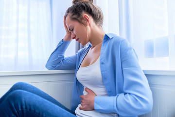Female suffering from stomach pain and strong spasm abdominal ache during gastric ulcer,...