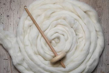 Foto auf Alu-Dibond Handspindel aus Holz mit einem naturfarbenem Kammzug aus Schafwolle zum selbst spinnen und handarbeiten © macrossphoto