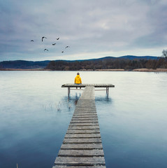 Frau sitzt einsam am See