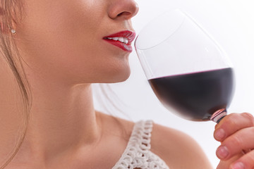 Drinking woman with red lips enjoys a glass of dry red wine close up
