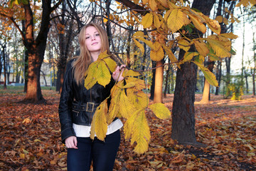 Girl in autumn park with a chestnut branch - yellow leaves