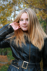Girl - a natural blonde with long hair in a black jacket straightens her hair