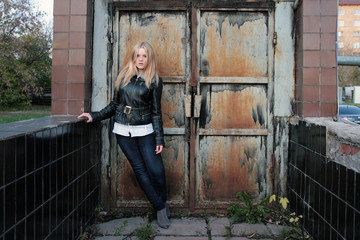 Modern, fashionable girl - blonde stands at the iron gate in the gateway