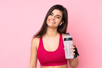 Young sport woman over isolated pink background with sports water bottle