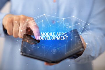 Businessman holding a foldable smartphone with MOBILE APPS DEVELOPMENT inscription, new technology concept
