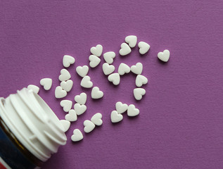 pills in the form of a heart scattered from an open can