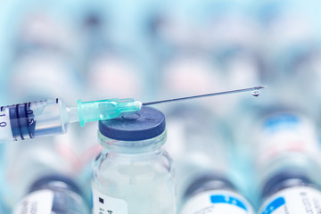 Syringe over medicine bottles on a blue background