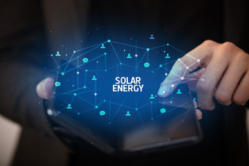 Businessman holding a foldable smartphone with SOLAR ENERGY inscription, new technology concept