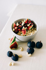 healthy Breakfast oatmeal with figs and cashews on a white table. vegan food