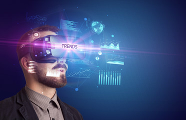 Businessman looking through Virtual Reality glasses with TRENDS inscription, new business concept