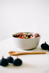 a plate of healthy Breakfast with oatmeal, figs and cashew nuts on a white table with a bamboo spoon. vegan food