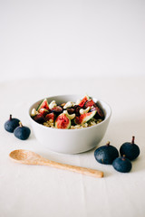 a plate of healthy Breakfast with oatmeal, figs and cashew nuts on a white table with a bamboo spoon. vegan food
