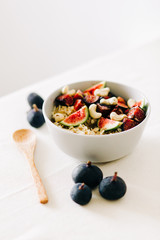 a bowl of healthy Breakfast with oatmeal, figs and cashew nuts on a white table with a bamboo spoon. vegan food