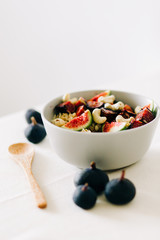 a bowl of healthy Breakfast with oatmeal, figs and cashew nuts on a white table with a bamboo spoon. vegan food