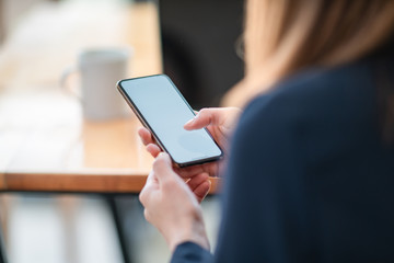 Woman sitting and holding blank screen mock up mobile phone	