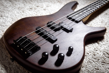 Bass guitar with four strings. Popular rock musical instrument. Close view of brown electric bass...
