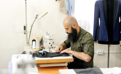 Naklejka na ściany i meble A tailor in a sewing workshop at work. His Studio is Sunny.
