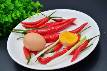 Red pepper and open eggs in a white porcelain plate