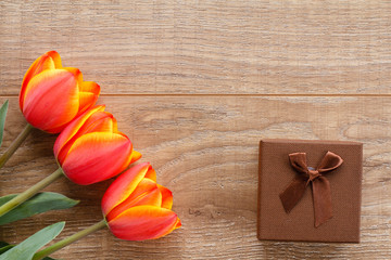 Gift box with red tulips on wooden boards.