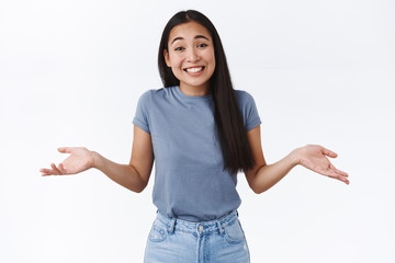 Cute carefree, relaxed smiling asian woman shrugging, tilt head silly and spread hands sideways...