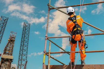 Rope access on scaffolding wearing safety harness, Construction worker wearing safety harness belt during working at high. on structur rig driling platform background.