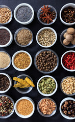 Spices and herbs flat lay, black background, top view.