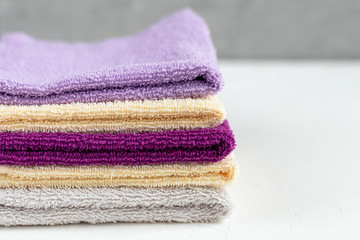 Terry towels for beauty and health. A stack of multi-colored towels lies on a white background....